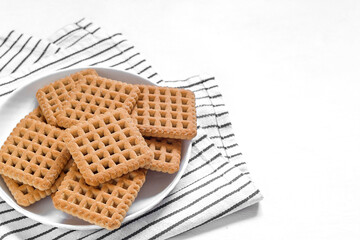 Sugary crunchy square biscuits on a plate on a white background. Copy space.