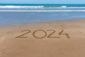 2024 written in the sand on the seashore with the arrival of the wave.
