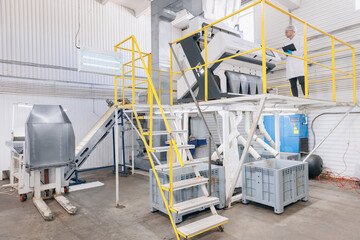 Modern electrical mill machinery for production. Operator checks finished food products wheat flour