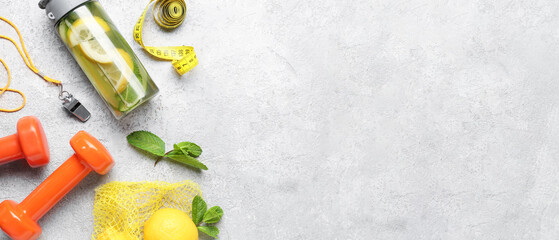 Sports bottle of lemonade with cucumber, whistle and dumbbells on grunge background with space for...
