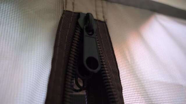 black zipper with a large double slider at the entrance to a light tent