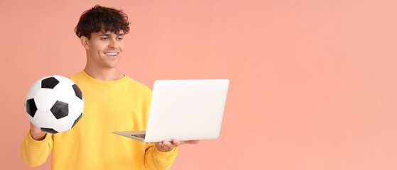 Young man with soccer ball and laptop on pink background with space for text