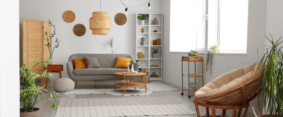 Obraz na płótnie Canvas Interior of light living room with grey sofa, coffee table and houseplants