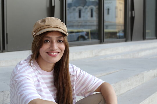 Fashionable woman wearing a beige beret style hat and striped pink and white t-shirt 