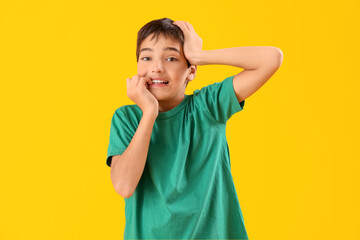 Little boy biting nails on yellow background