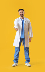 Male dentist holding something on yellow background