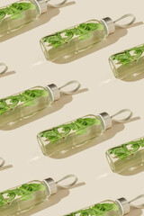 Pattern from Glass bottle with green mint leaves water drink detox at sunlight on beige background, sun glare. Natural Infused water Healthy drink. Aesthetic still life, refreshing summer drink