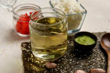 Bottle of rice vinegar and ingredients for preparing sushi rolls on light table, closeup