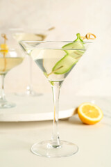 Glass of tasty martini and lemon on white table
