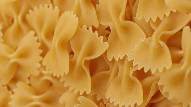 dry pasta farfalle , rotation in circle. Turning pasta background. selective focus, vertical video