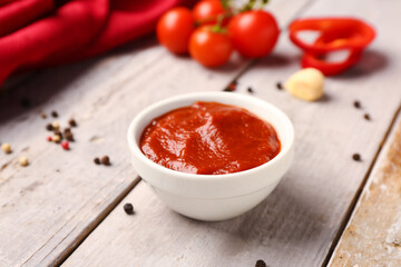 Bowl with tasty tomato paste on light wooden background