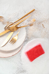 Cleaning sponge with dishes and foam in water, closeup