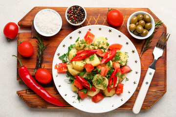 Plate of tasty Potato Salad with vegetables and ingredients on light background