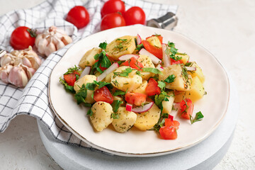Plate of tasty Potato Salad with vegetables on light background