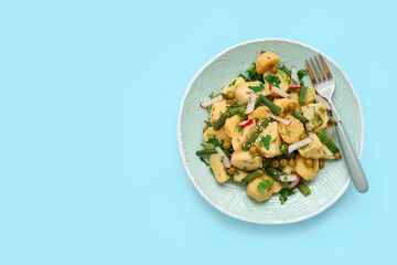Plate of tasty Potato Salad with vegetables on blue background