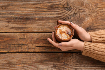 Woman with cup of coffee on wooden background