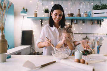 Smiling woman cooking in kitchen with daughter