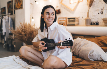 Female playing ukulele in bedroom