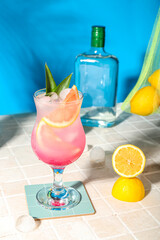 Fresh summer cocktail with grapefruit on tile table near blue wall