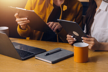 Female students note from the books at the Asian girl library sitting at sofa using laptop computer and tablet to search an online informations. in living room