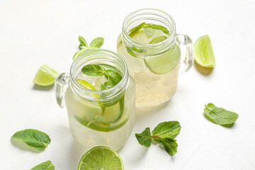 Mason jars of tasty mojito on light background