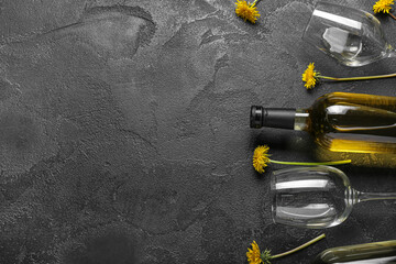 Bottle and glasses of dandelion wine on black background