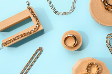 Decorative podiums with beautiful jewellery on blue background