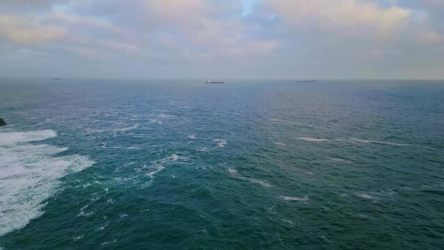 Cold gray ocean rippling under heavy cloudy sky drone. Ship floating in distance