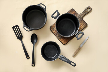 Cooking pots and kitchen utensils on beige background