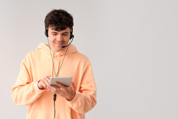 Male technical support agent with tablet computer on grey background