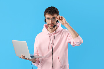 Male technical support agent with laptop on blue background