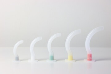 Oropharyngeal airway cannula in a white surface aligned by the size of each cannula. Small to big...