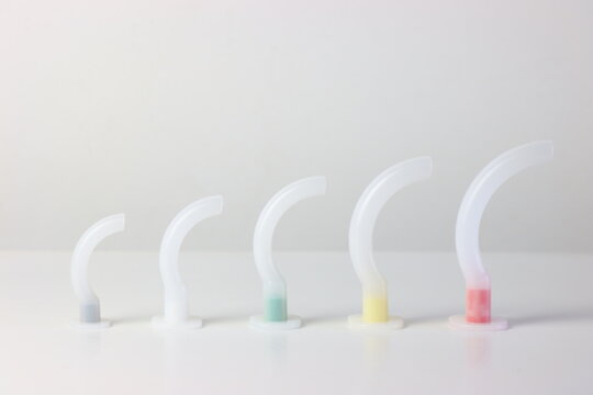 Oropharyngeal airway cannula in a white surface aligned by the size of each cannula. Small to big size. 0 to 5 size of a guedel cannula 