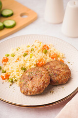 Cutlets with bulgur and boiled vegetables on light table in kitchen