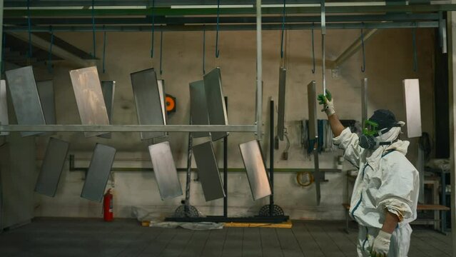 Worker pushing line of painted metal sheets into the drying chamber. Creative. Steel production plant.