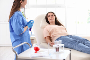 Female nurse with belt for blood transfusion and young donor in clinic