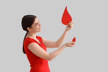 Female donor with paper blood drops on light background