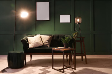 Interior of dark living room with green sofa and glowing lamps