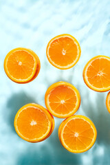 Slices of fresh orange in water on blue background