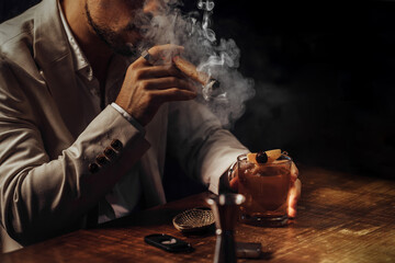 Man smoking a cigar and having an old-fashioned cocktail served on a wooden bar table
