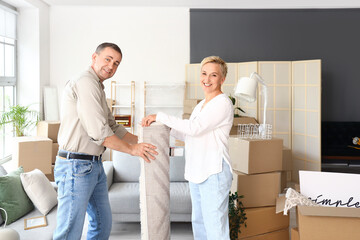 Mature couple packing carpet in room on moving day