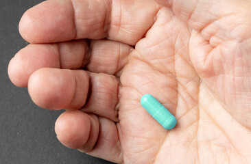 Pill in wrinkled old hand close up view