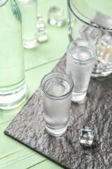 Glasses of cold vodka on green wooden background
