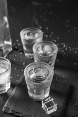 Shots of vodka with ice cubes on black background