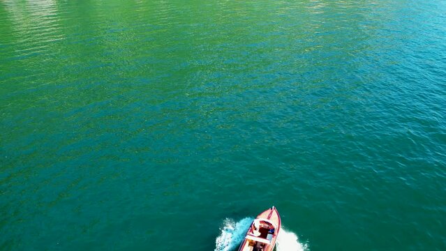 Aerial 4K footage of a classic old wooden luxury fast sailing boat in Lake Como