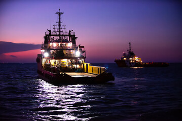 Cargo ship on the sea arriving to the harbor by night
