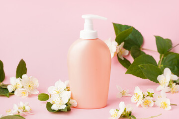 Obraz na płótnie Canvas Bottle of cosmetic product and jasmine flowers on pink background