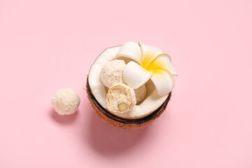Fototapeta na wymiar Coconut with white chocolate candies and plumeria flower on pink background