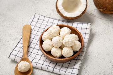 Wooden bowl with delicious coconut candies on white table
