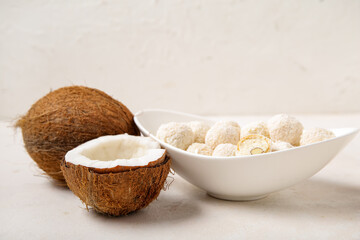 Bowl with white chocolate candies and coconuts on light table